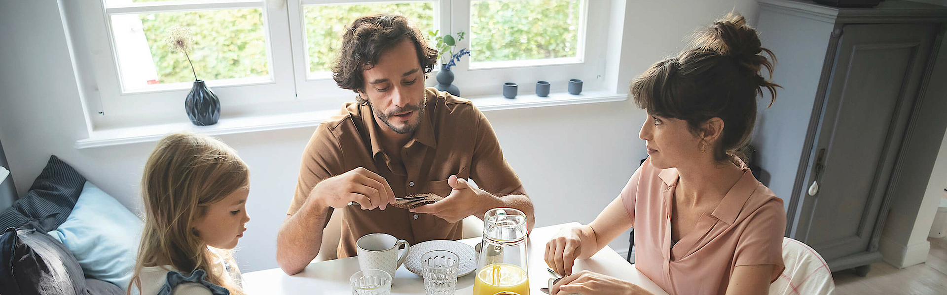 Eine Familie sitzt gemeinsam am Frühstückstisch und genießen das gemeinsame Essen.