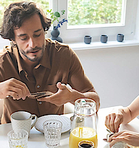 Eine Familie sitzt gemeinsam am Frühstückstisch und genießen das gemeinsame Essen.