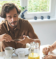 Eine Familie sitzt gemeinsam am Frühstückstisch und genießen das gemeinsame Essen.