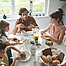 Eine Familie sitzt gemeinsam am Frühstückstisch und genießen das gemeinsame Essen.
