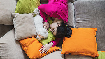 Frau mit unregelmäßigem Schlafrhythmus liegt auf Sofa